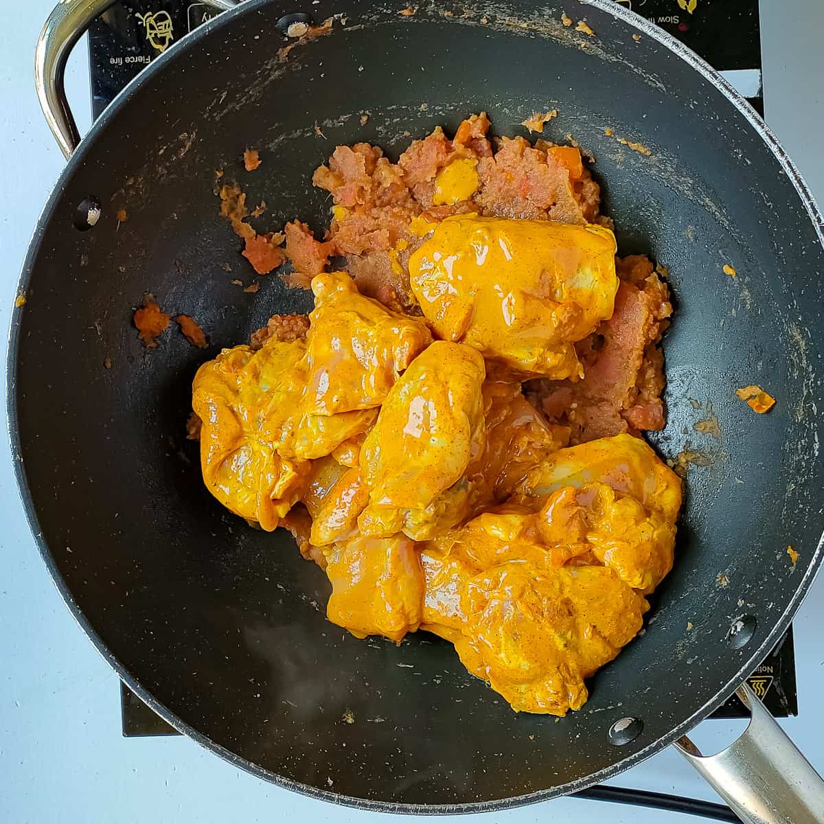 Marinated chicken being sauteed in a wok