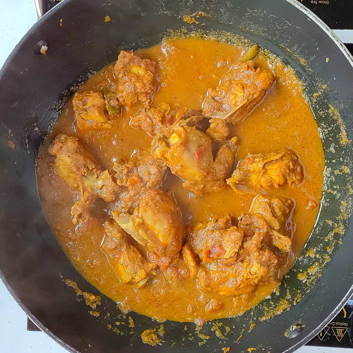 Pepper chicken with gravy simmering in a wok.