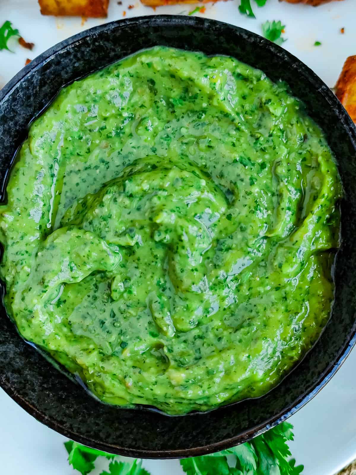 Avocado chutney in a black bowl.