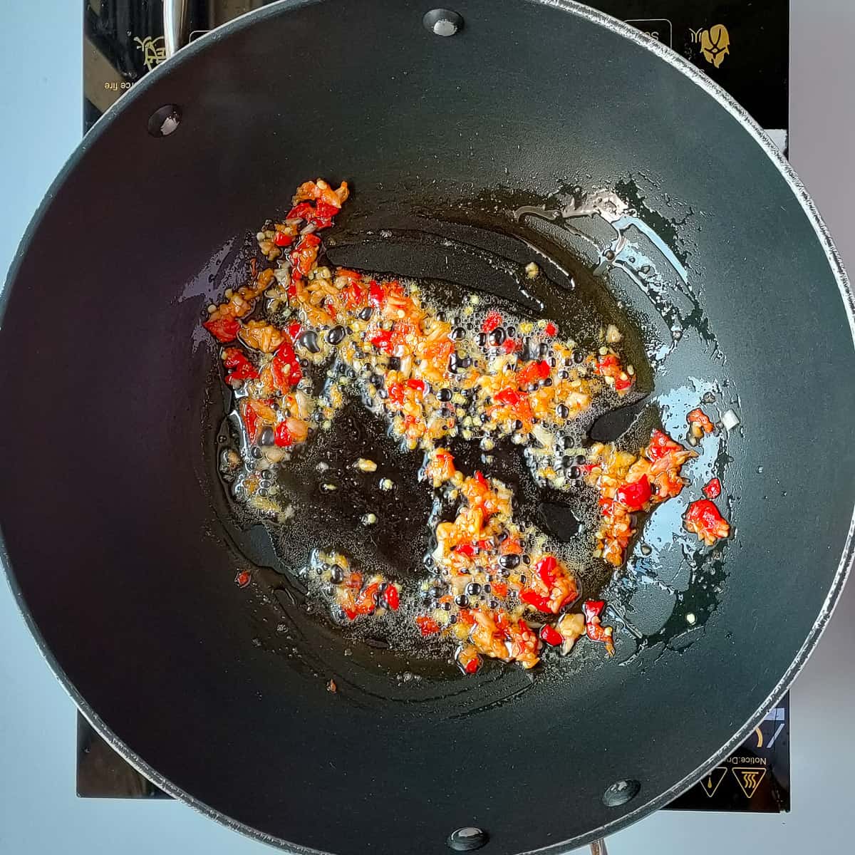 Chili garlic paste being fried in wok.