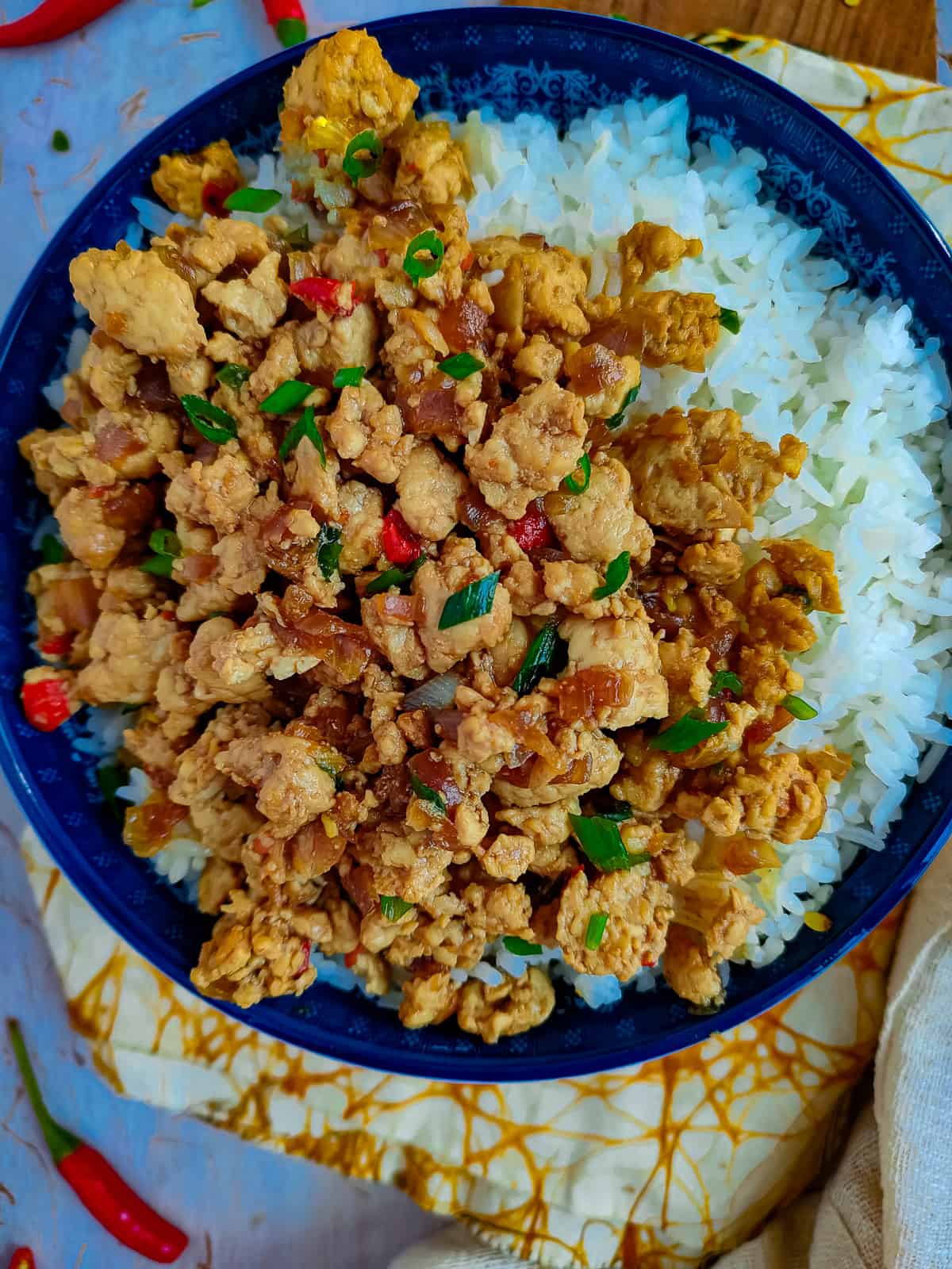 Stir fry with minced chicken in a blue bowl with rice.