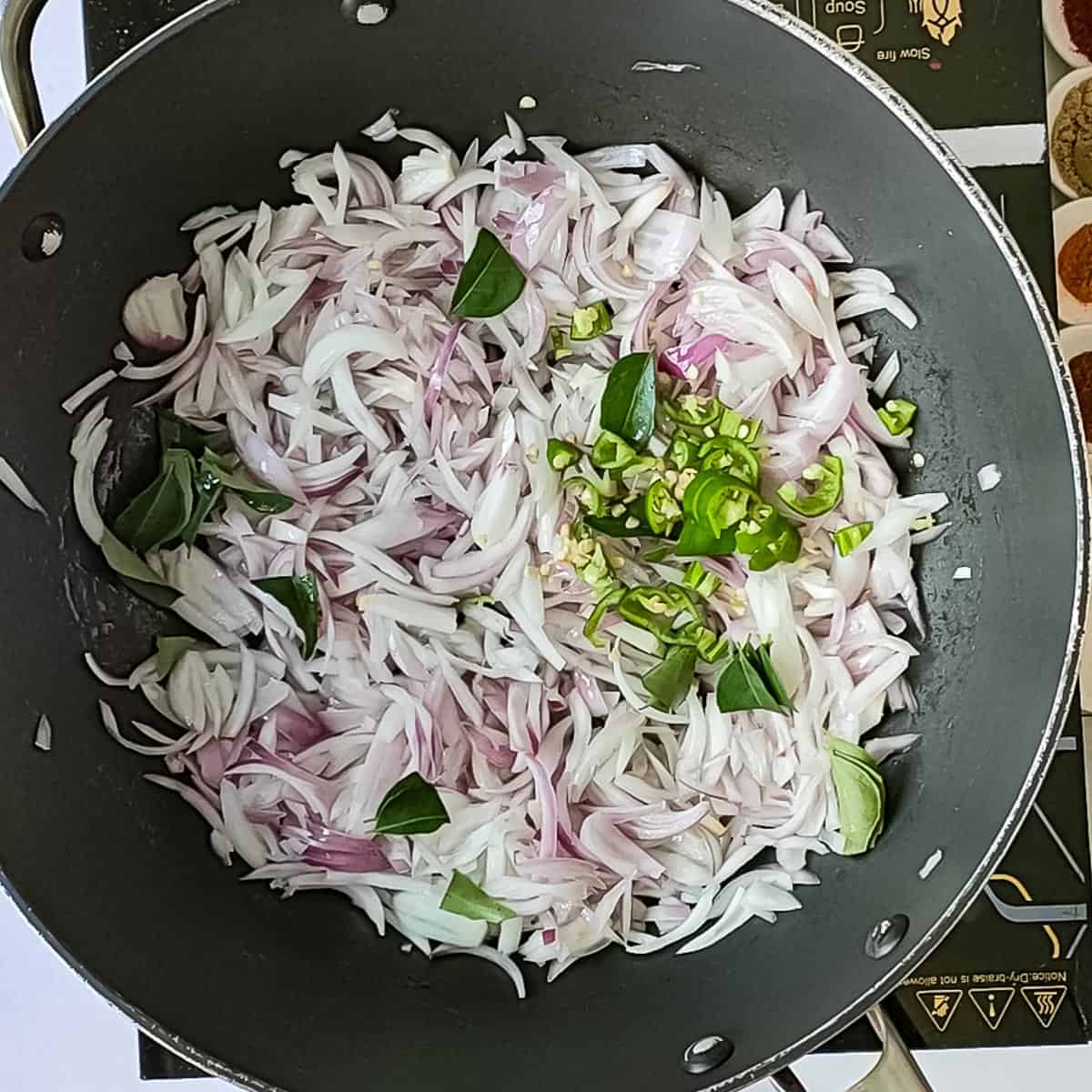 Green chillies added to sauteed onions in a wok.