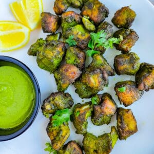 Hariyali chicken kebab with green chutney on a white plate.