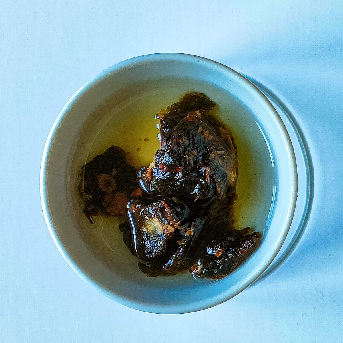 Tamarind soaked in water in a white bowl.