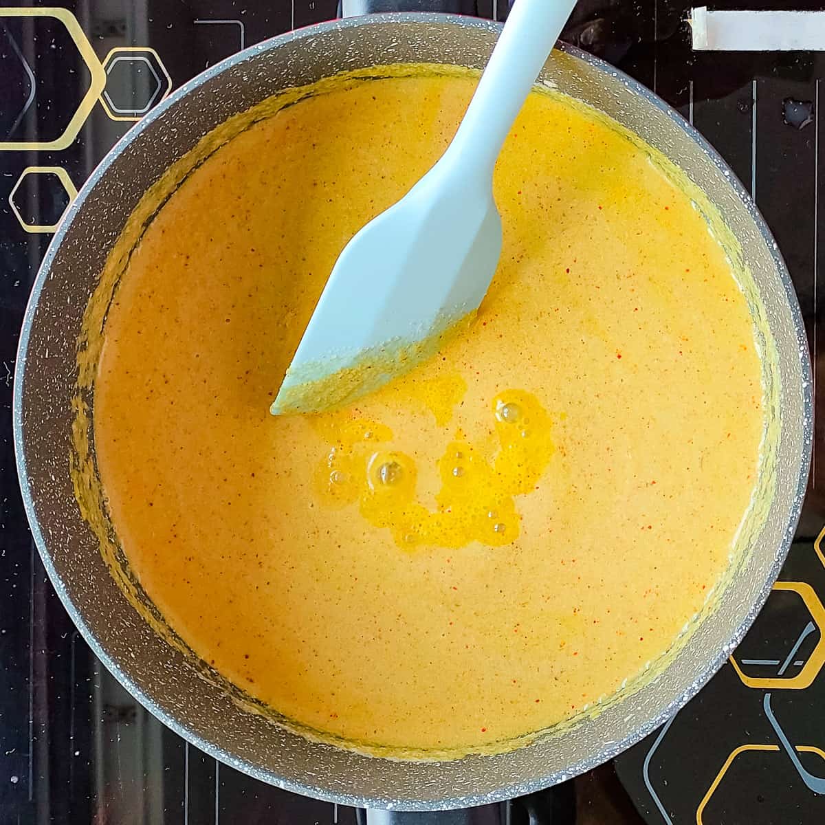 Kerala meen curry being stirred in a pot.