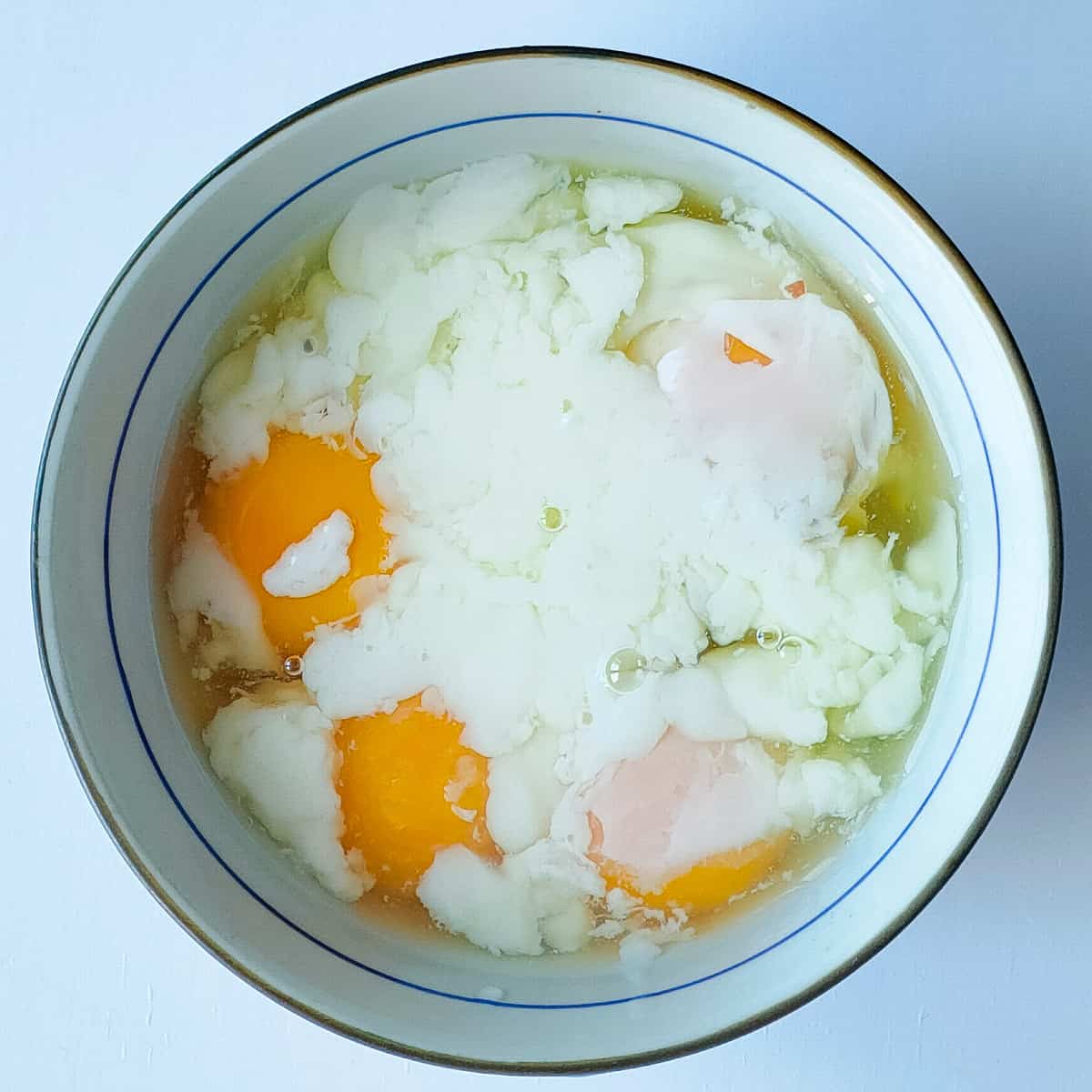 Half-boiled eggs in a white bowl.