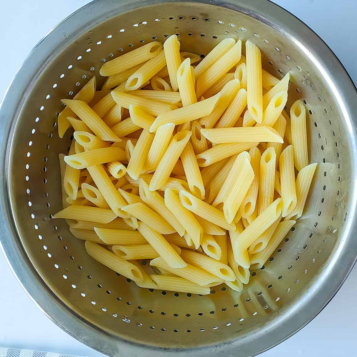 Cooked penne pasta in a colander.