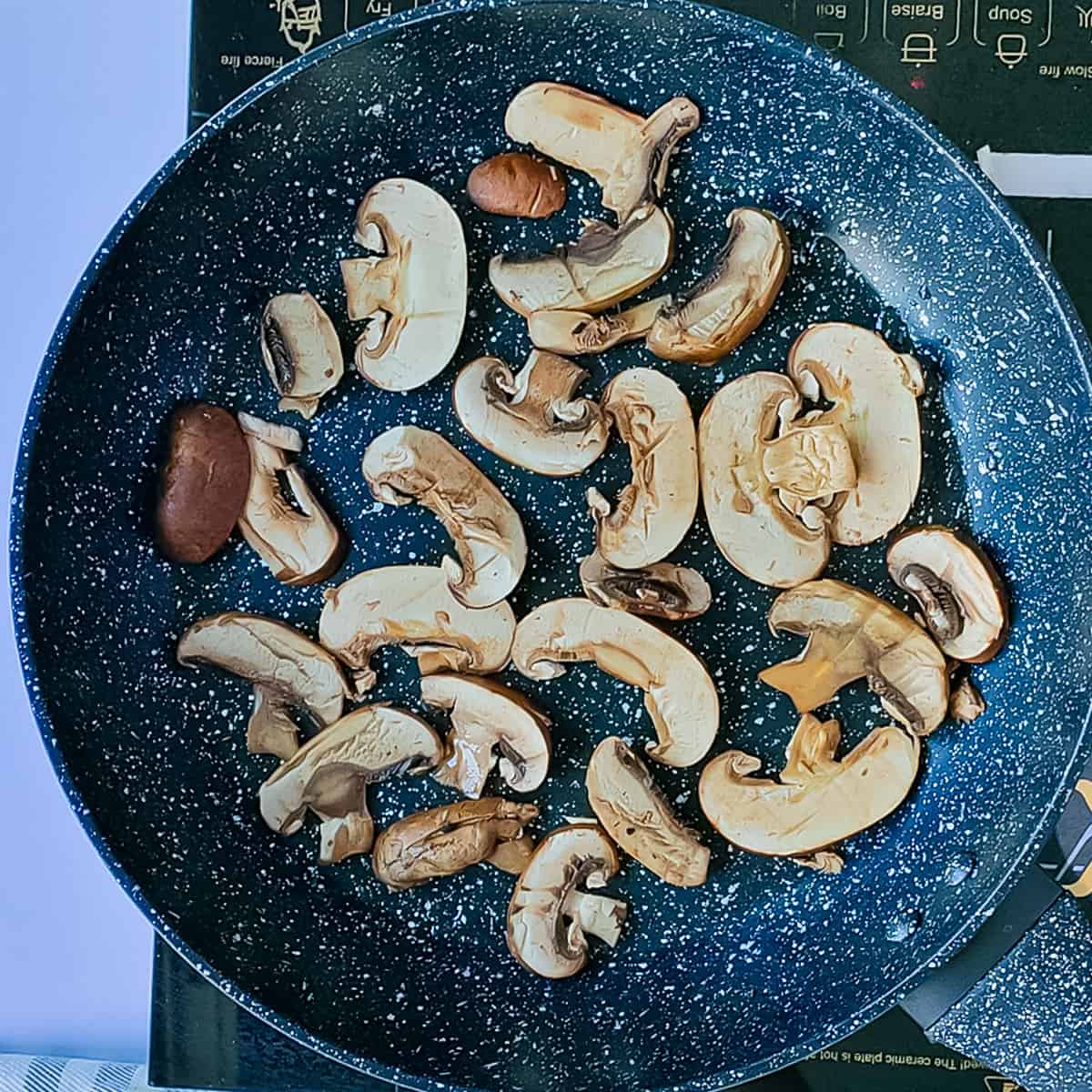 Mushrooms being sauteed in a pan.