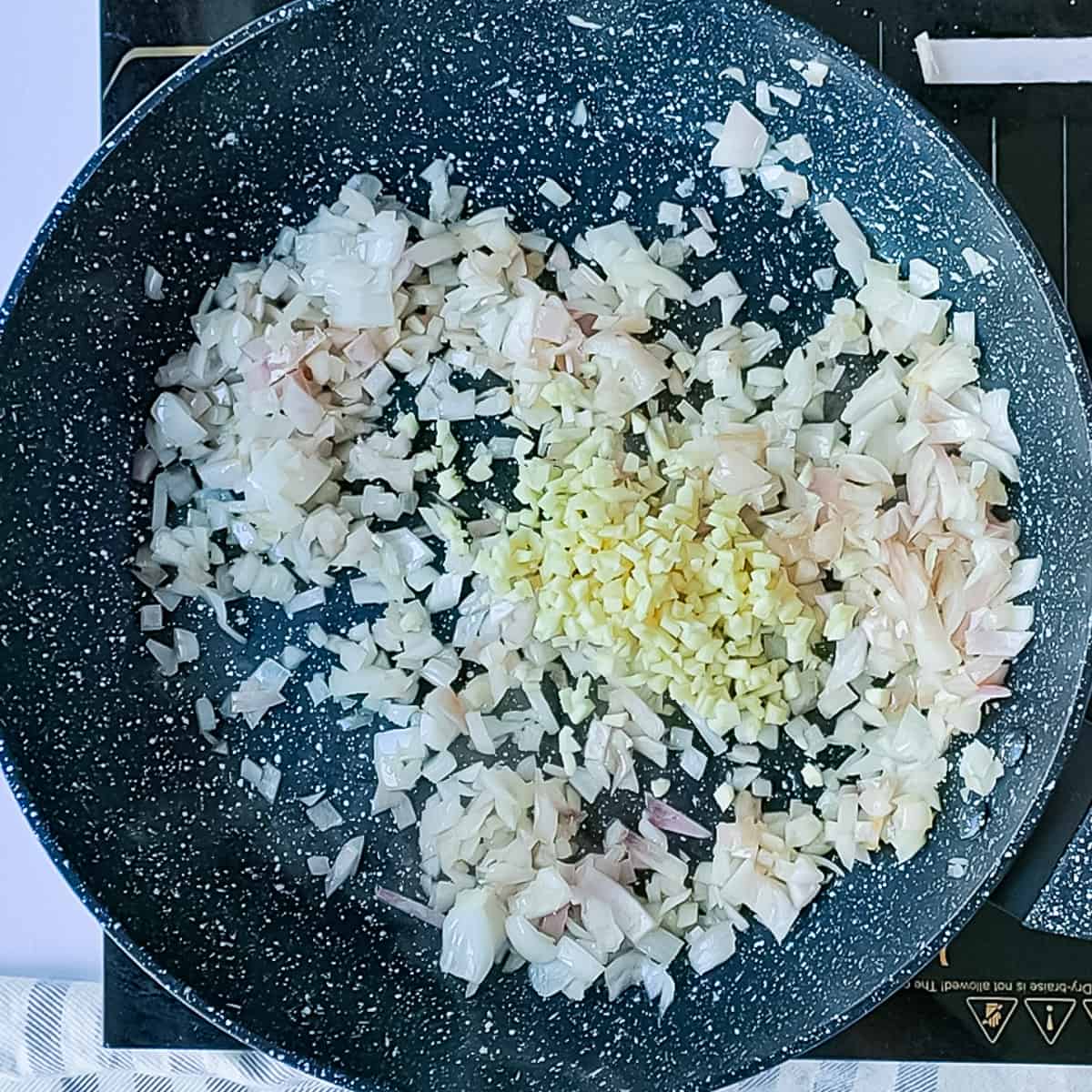 Garlic and onions being sauteed in a pan.