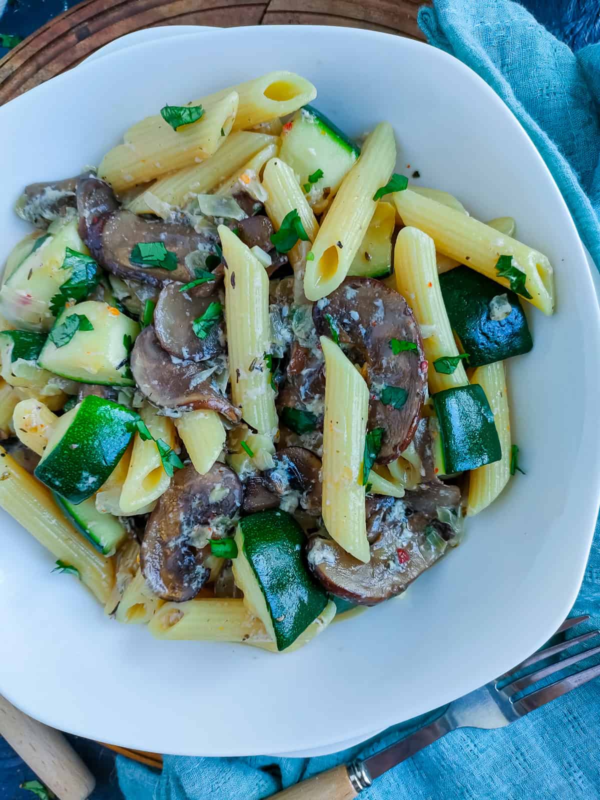 Zucchini mushroom pasta on a white plate.