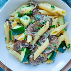 Zucchini mushroom pasta on a white plate.