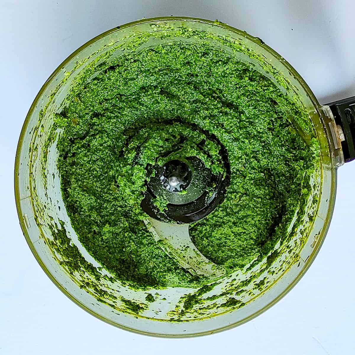 Blended spinach pesto in a food processor jar.