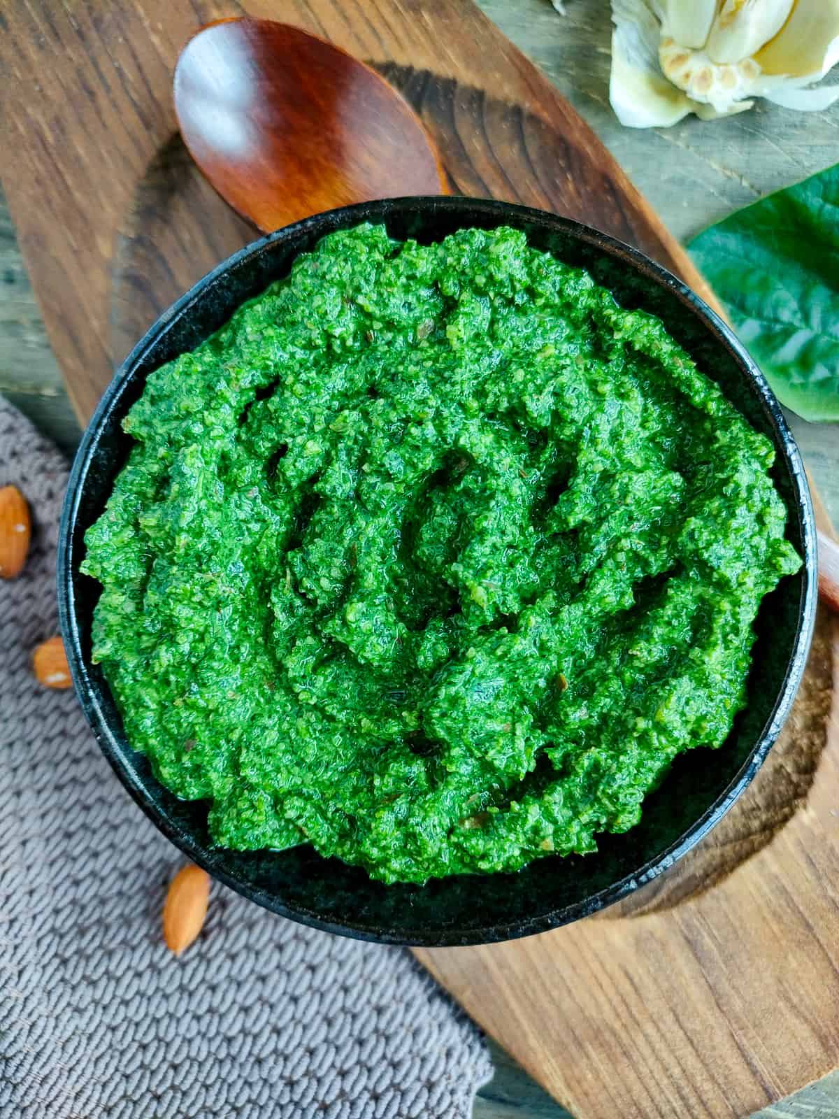 Basil almond pesto with spinach in a black bowl.