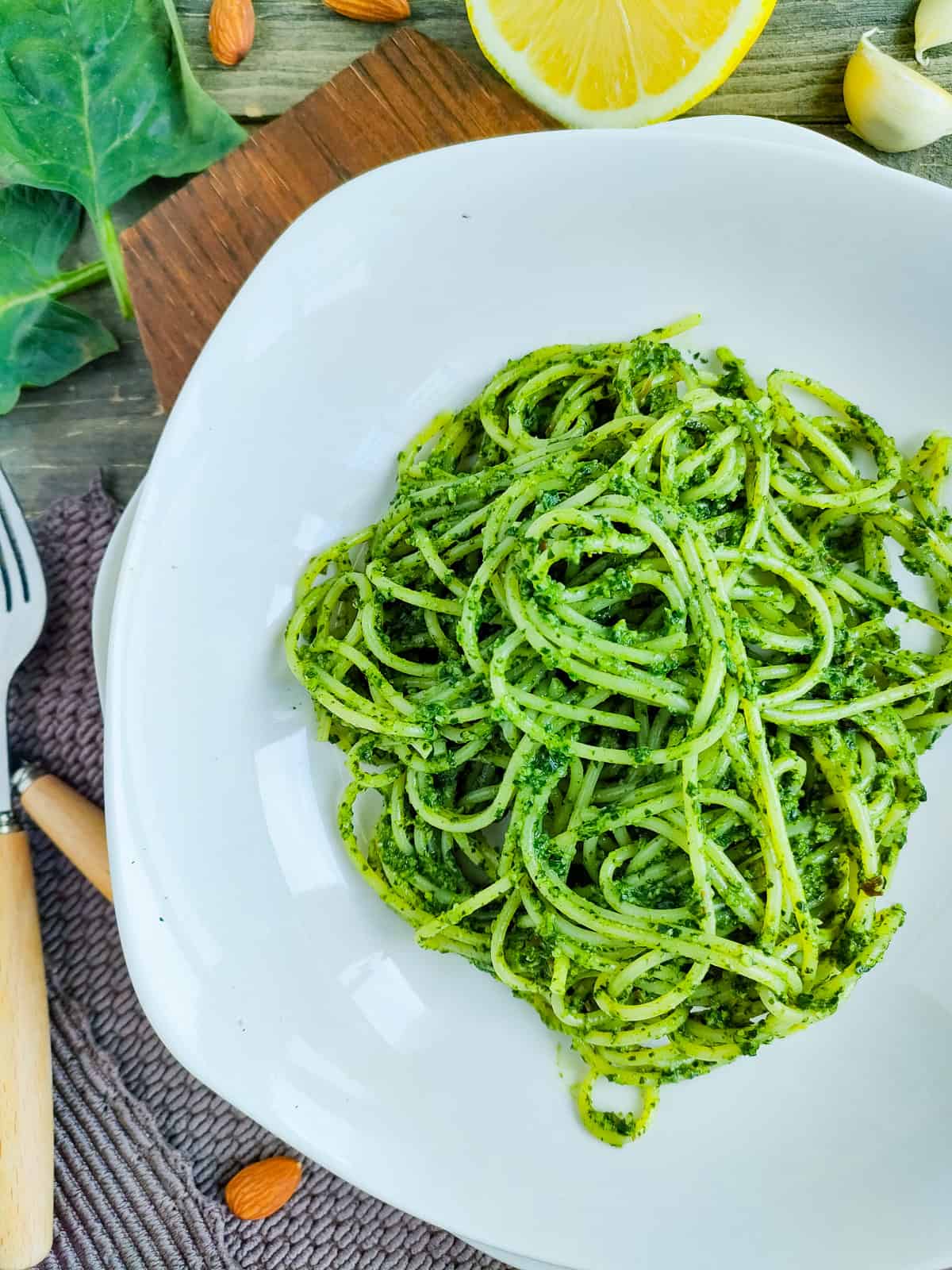 Almond pesto pasta with spinach on a white plate.