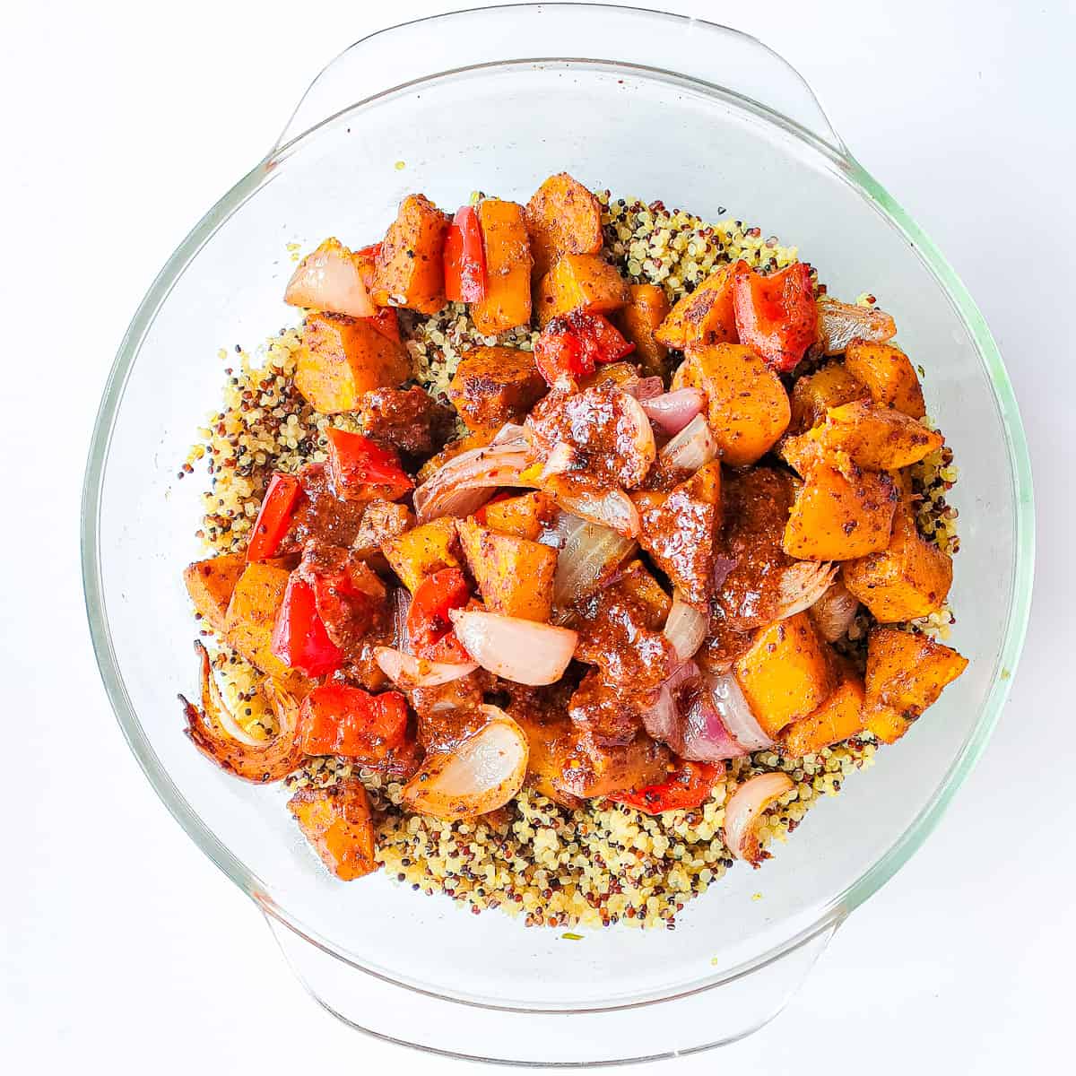 Honey lemon dressing drizzled on quinoa and roasted vegetables in a glass bowl.