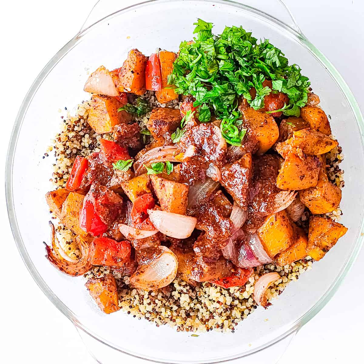 Pumpkin spice dressing drizzled on quinoa and roasted vegetables in a glass bowl.