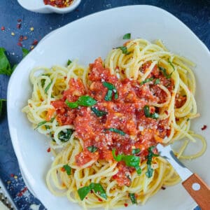 Spaghetti arrabiata on a white plate with a fork.