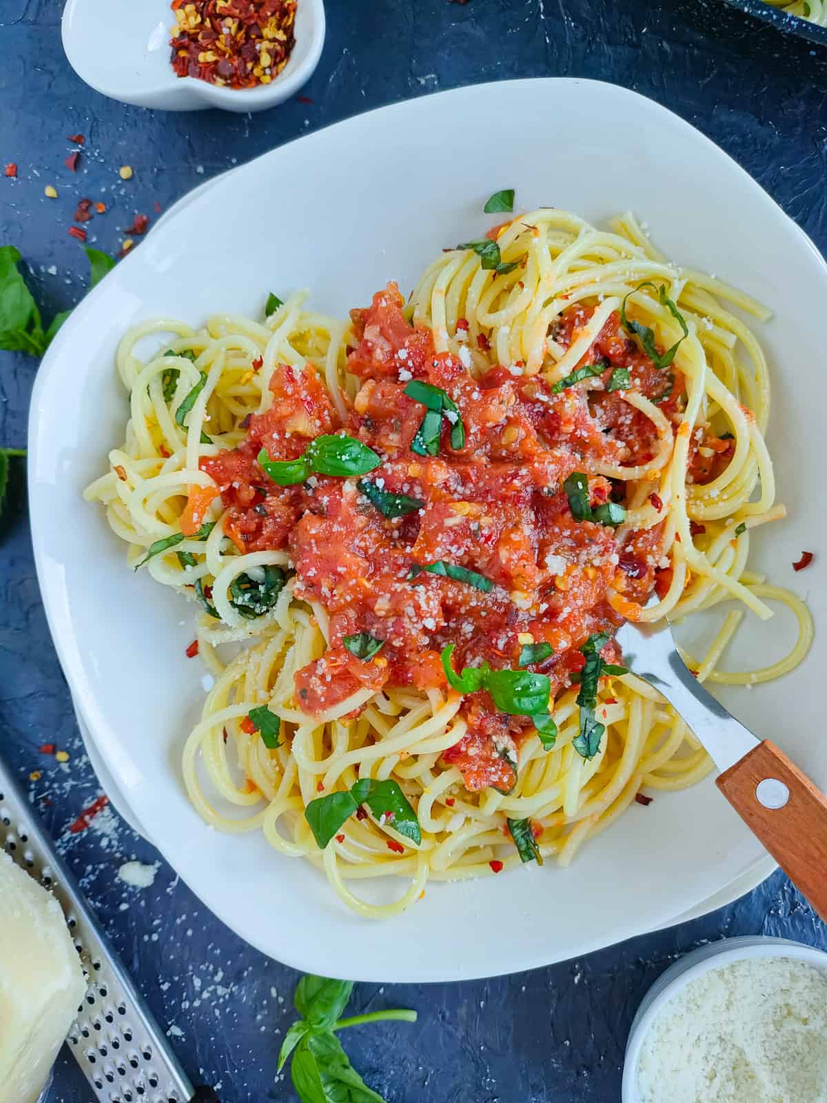 Spaghetti arrabiata on a white plate with a fork.