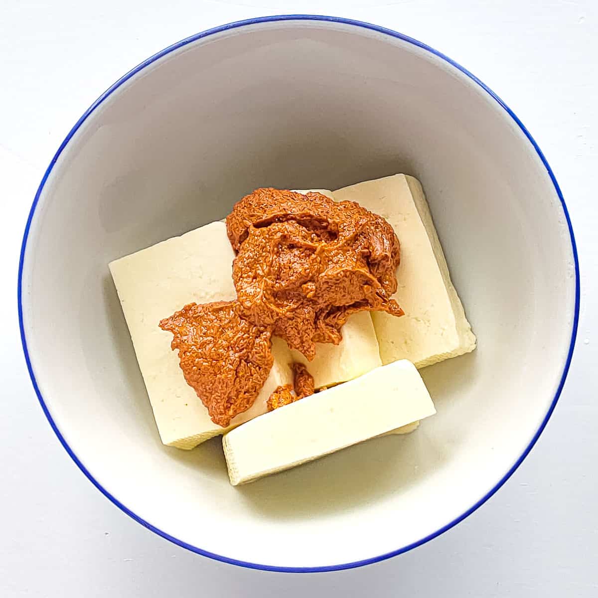 Paneer slabs with tandoori marinade in a bowl.