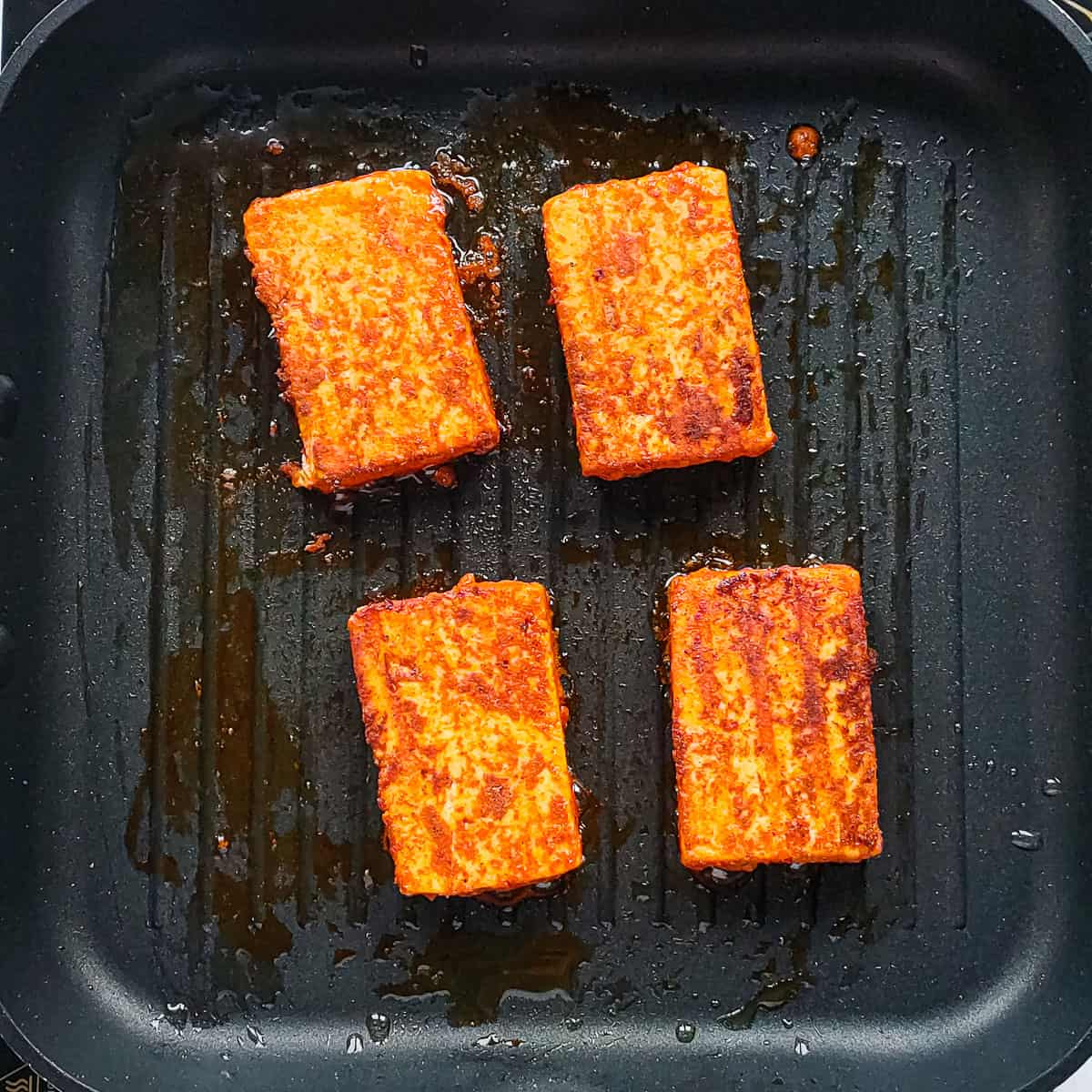 Paneer tikka being grilled on a grill pan.