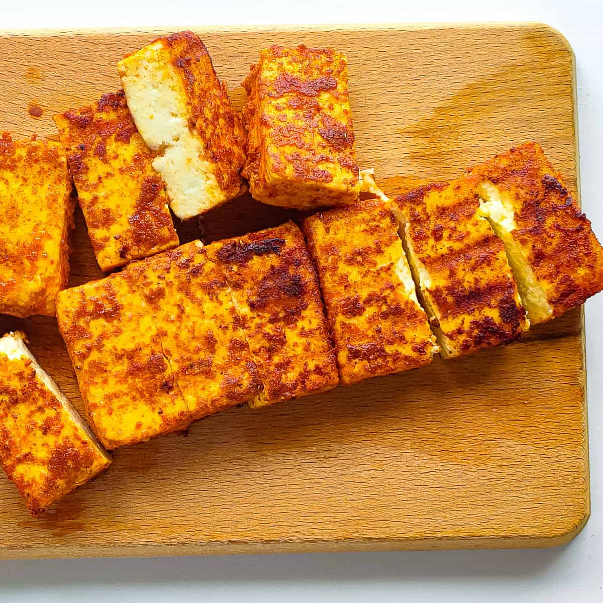 Paneer tikka on a wooden chopping board.