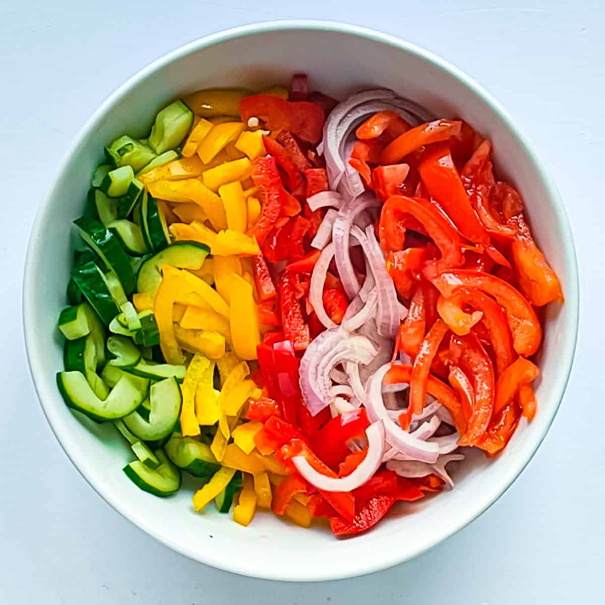 Sliced vegetables for paneer salad in a white bowl.