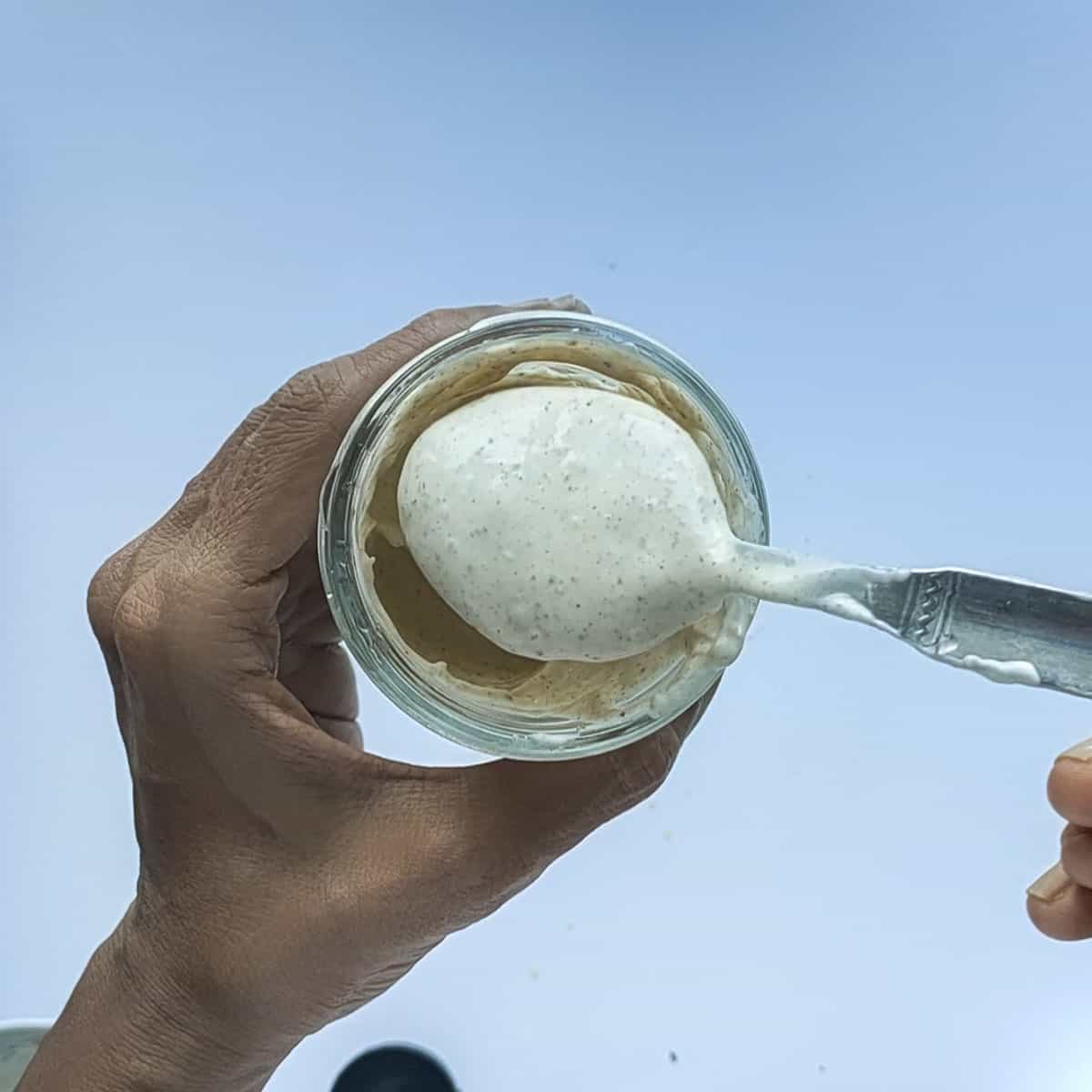 No oil salad dressing in a spoon scooped out from a glass jar.