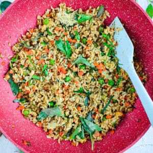 Green curry rice in a wok pan with a spatula in it.