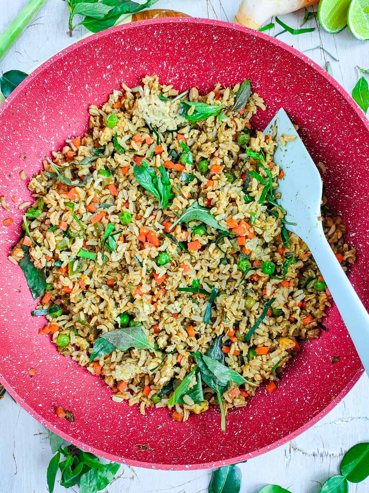 Thai Green Curry Fried Rice (with Brown Rice) Thai green curry rice in a wok pan with a spatula in it.