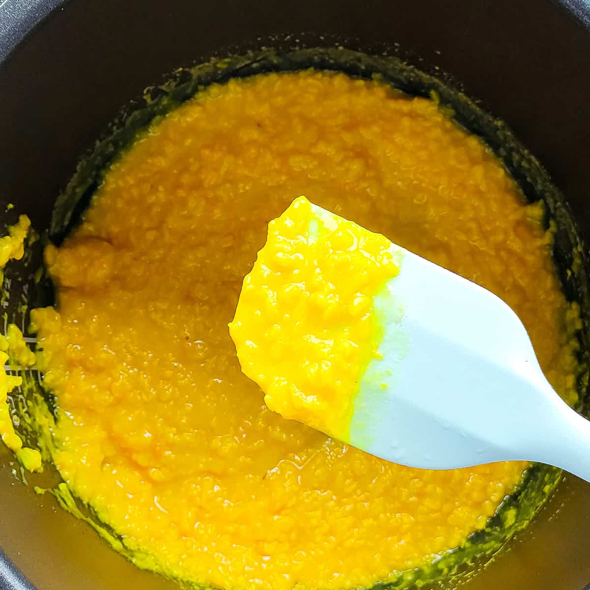 Cooked mung dal scooped out with a ladle from instant pot for Kerala dal curry.