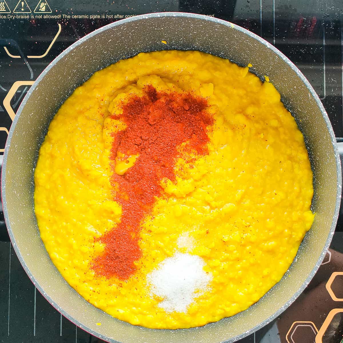 Cooked mung dal with chili powder and salt in a cooking pot.