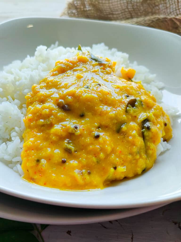 Kerala style parippu curry with rice on a white plate.