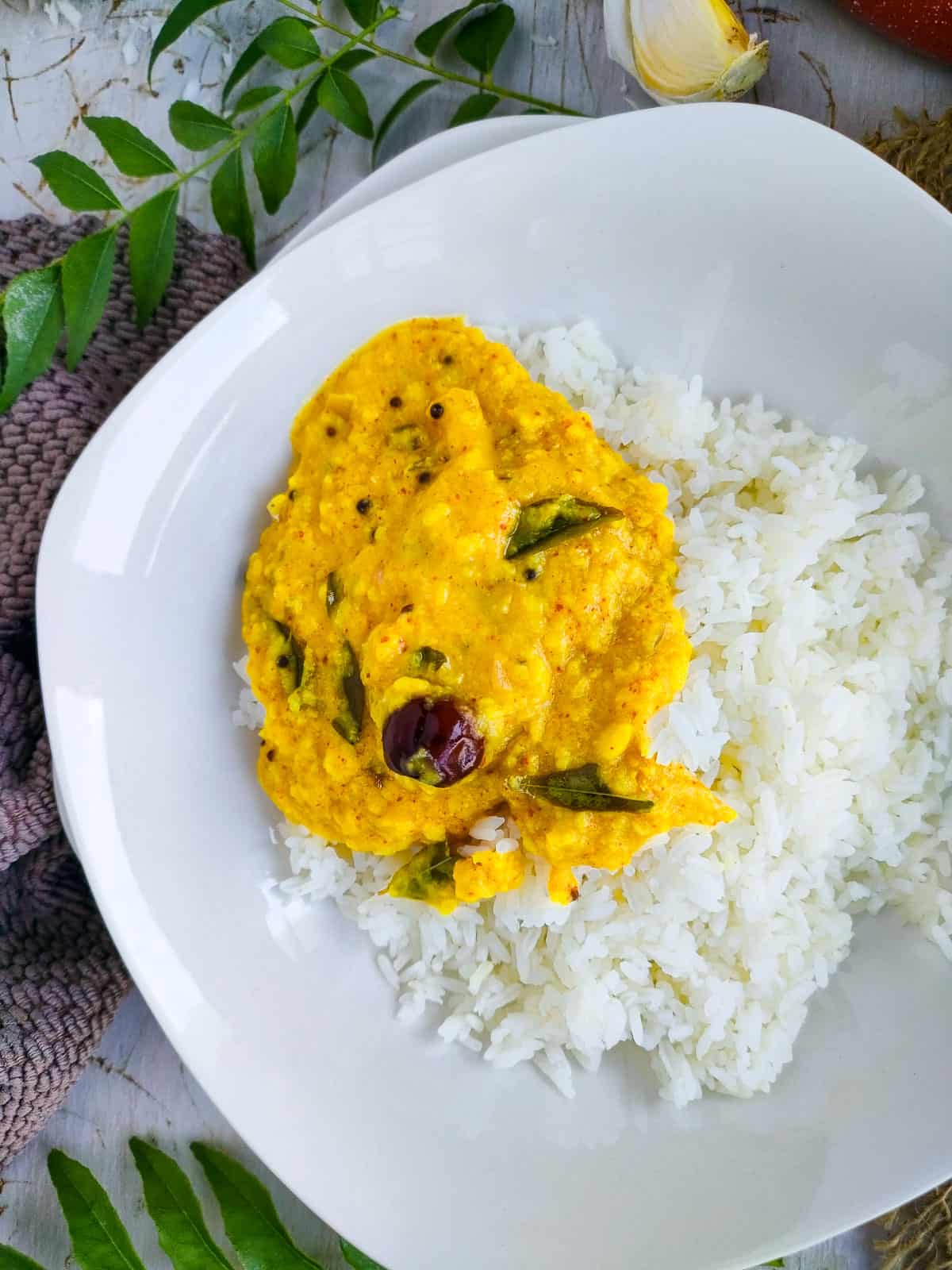 Sadya parippu curry with rice on a white plate.