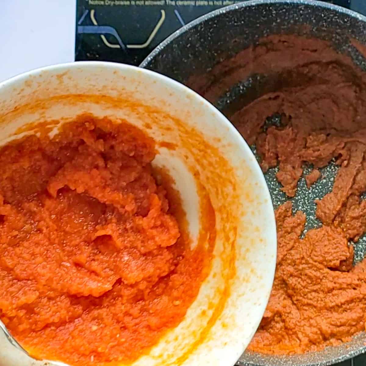 Tomato paste being added to fish masala in a cooking pot.