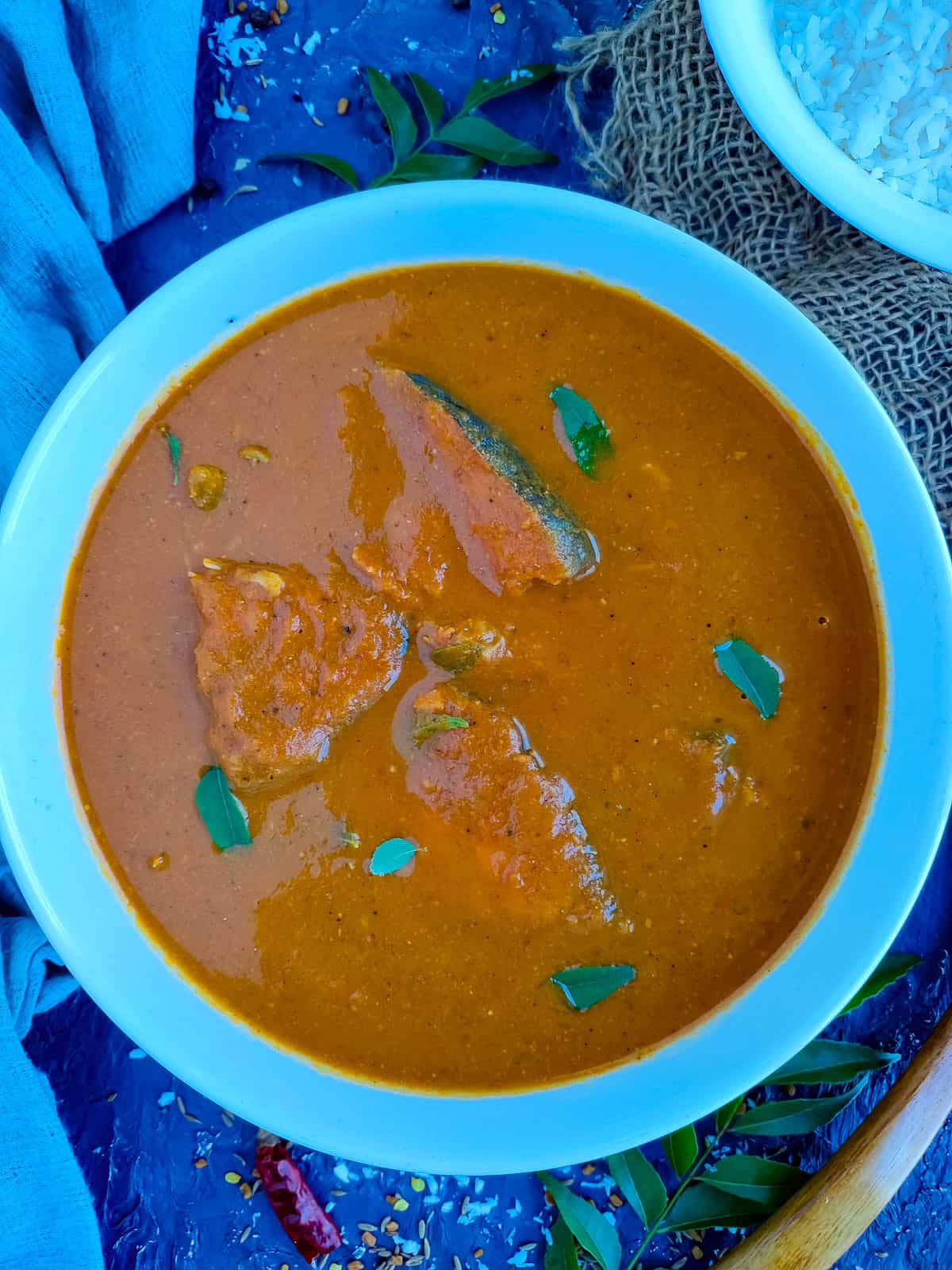 Mangalorean fish curry in a white bowl and a bowl of rice next to it.