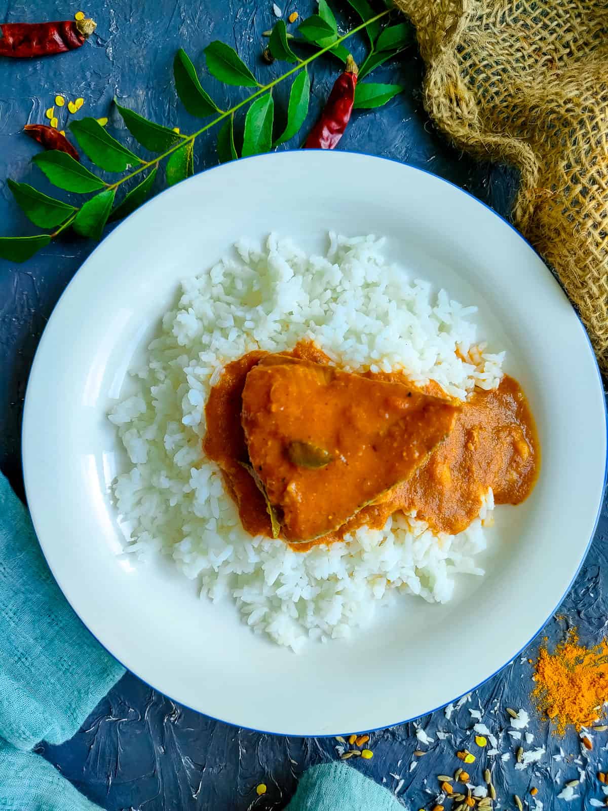 Mangalore style fish curry served with rice on a white plate.