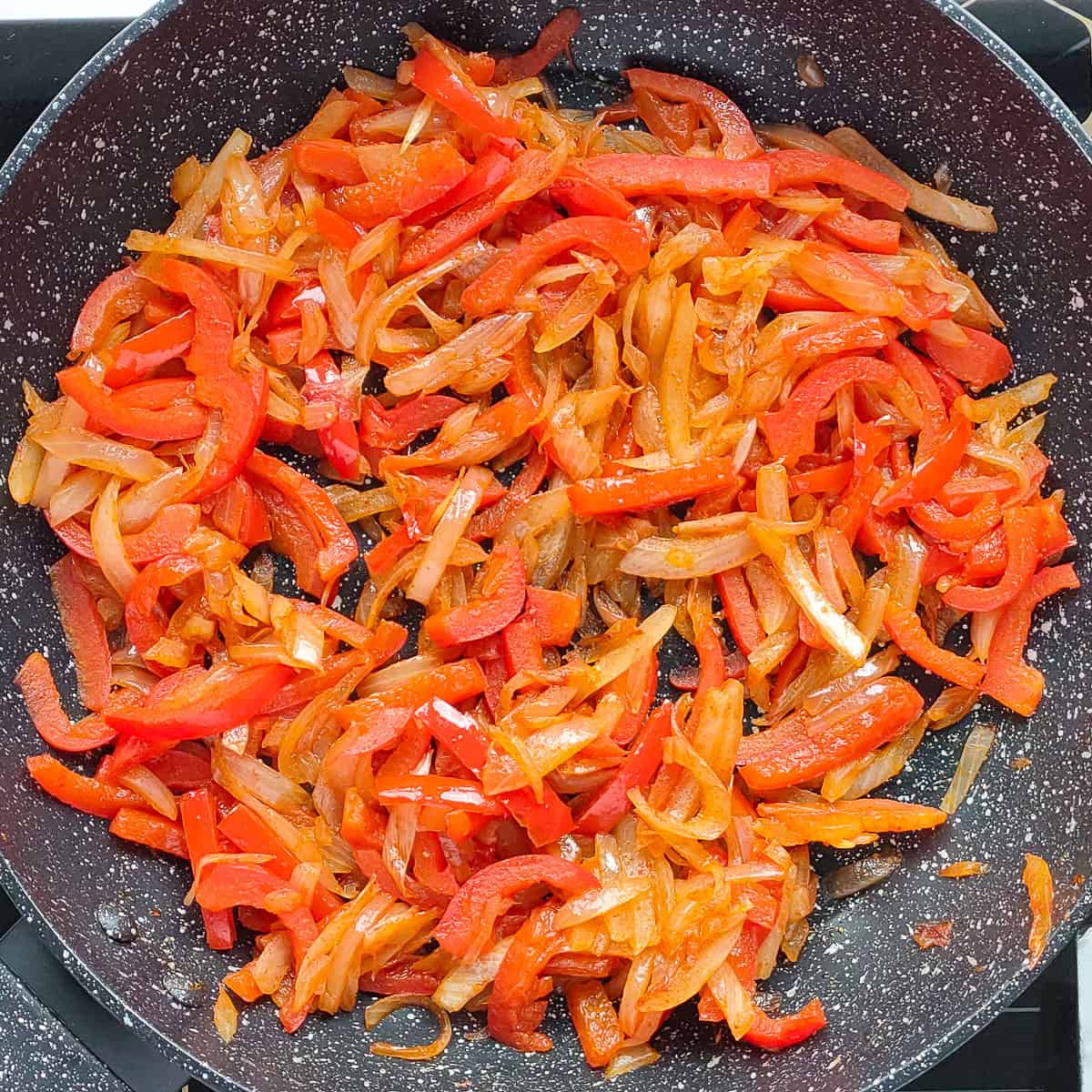 Caramelized onions and peppers in a pan.