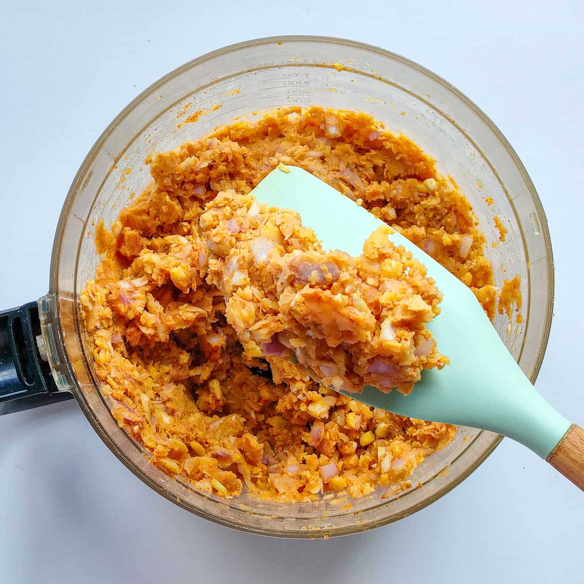 Processed chickpeas and spices in a food processor jar.