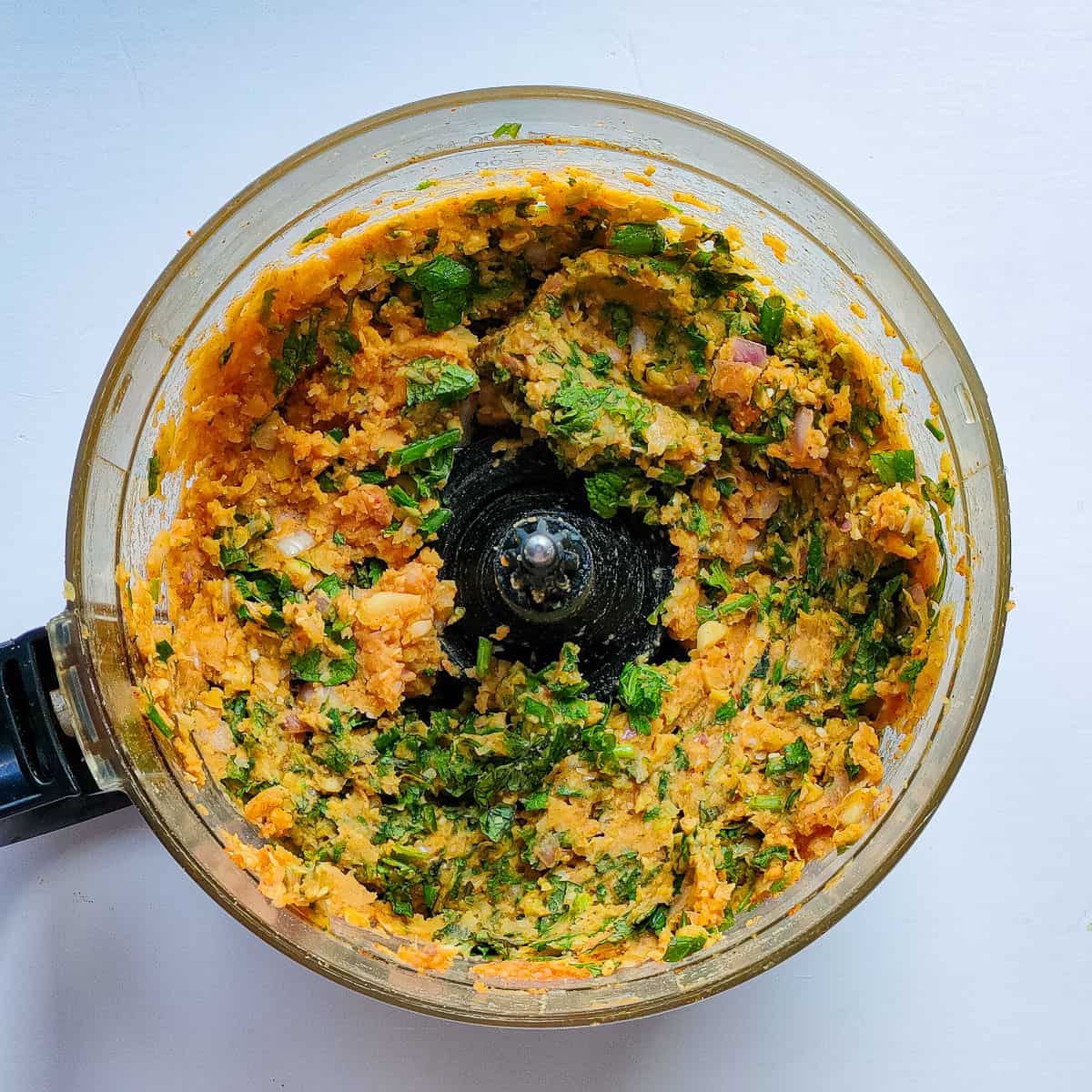 Mashed chickpeas with seasonings in a food processor jar.