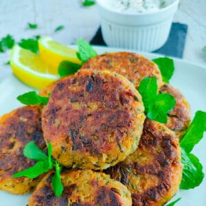 Chana tikki with lemon slices on an off-white plate.