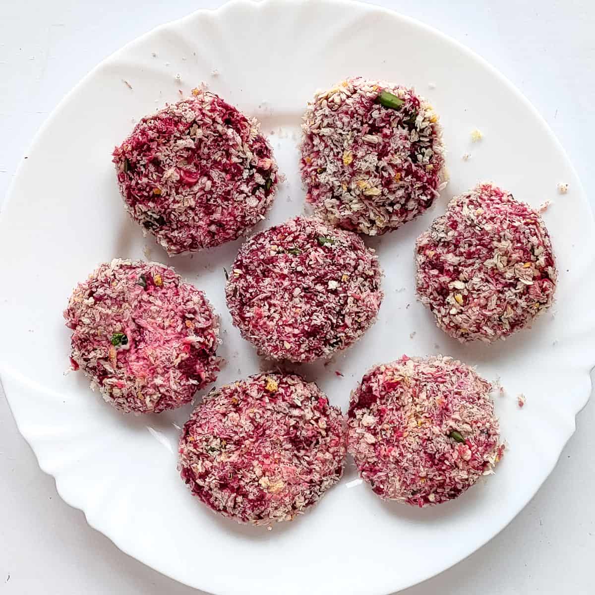 Beetroot tikki on a white plate before being baked.