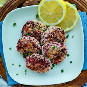 Beetroot tikki with lemon slices on an off-white plate.