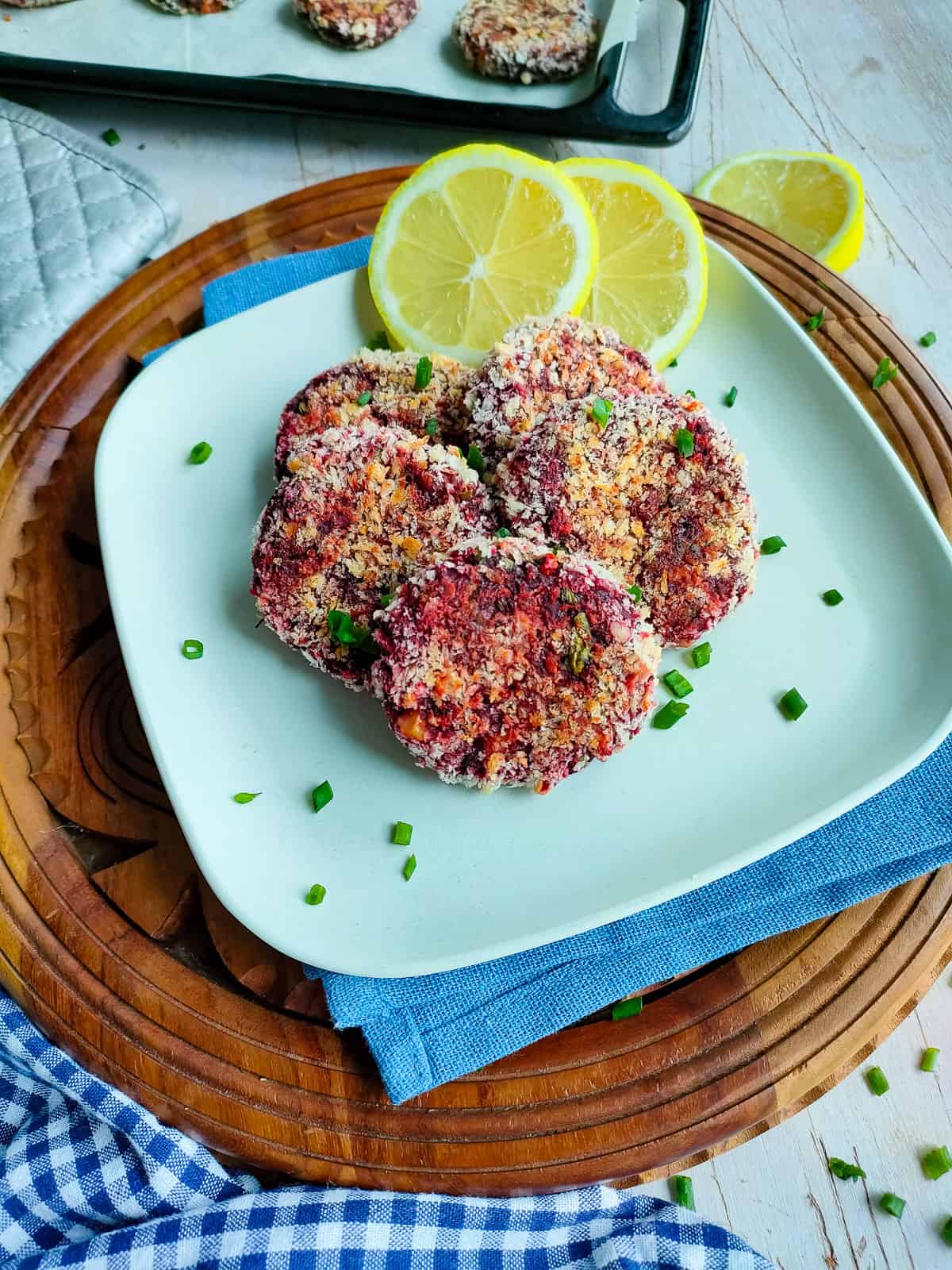 Beetroot kebabs with lemon slices on an off-white plate.