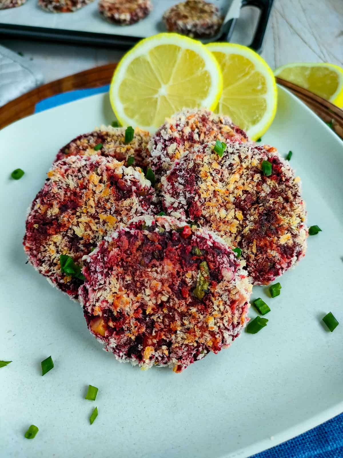 Beetroot tikki with lemon slices on an off-white plate.