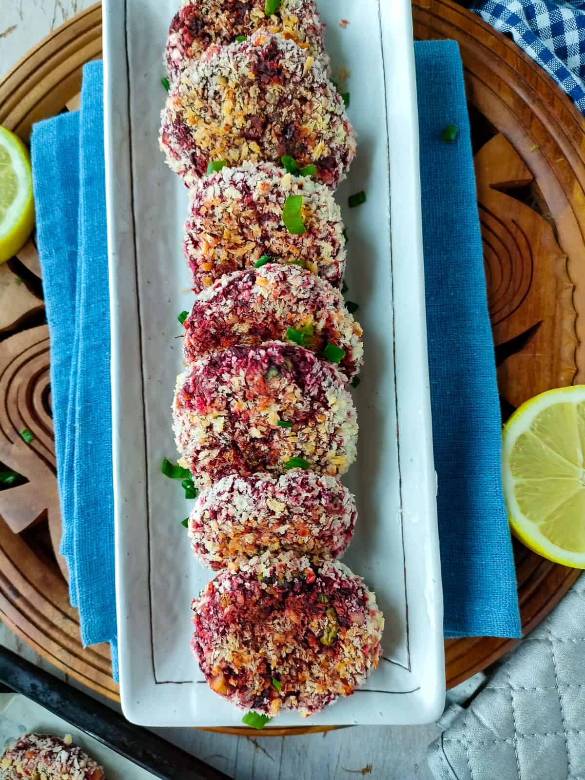 Beetroot patties with lemon slices on an off-white plate.