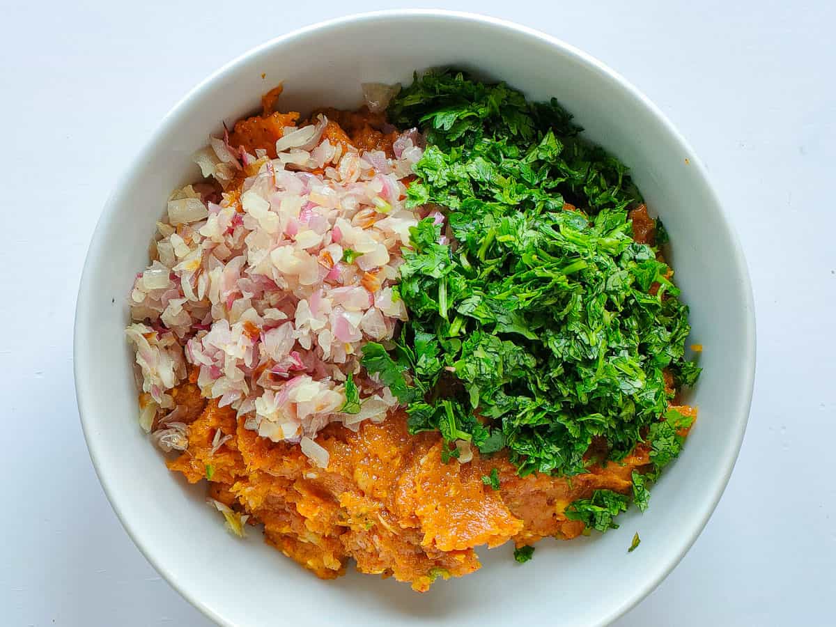 Minced chicken with sauteed onions and herbs in a white bowl.