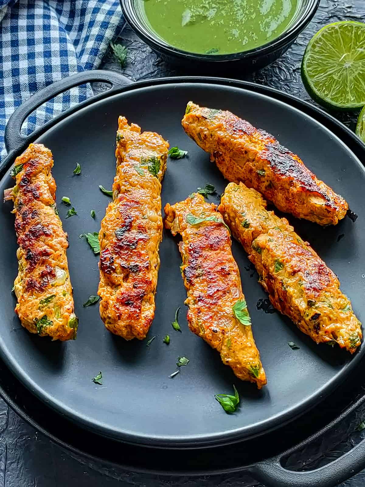 Minced chicken kebabs on a black plate.