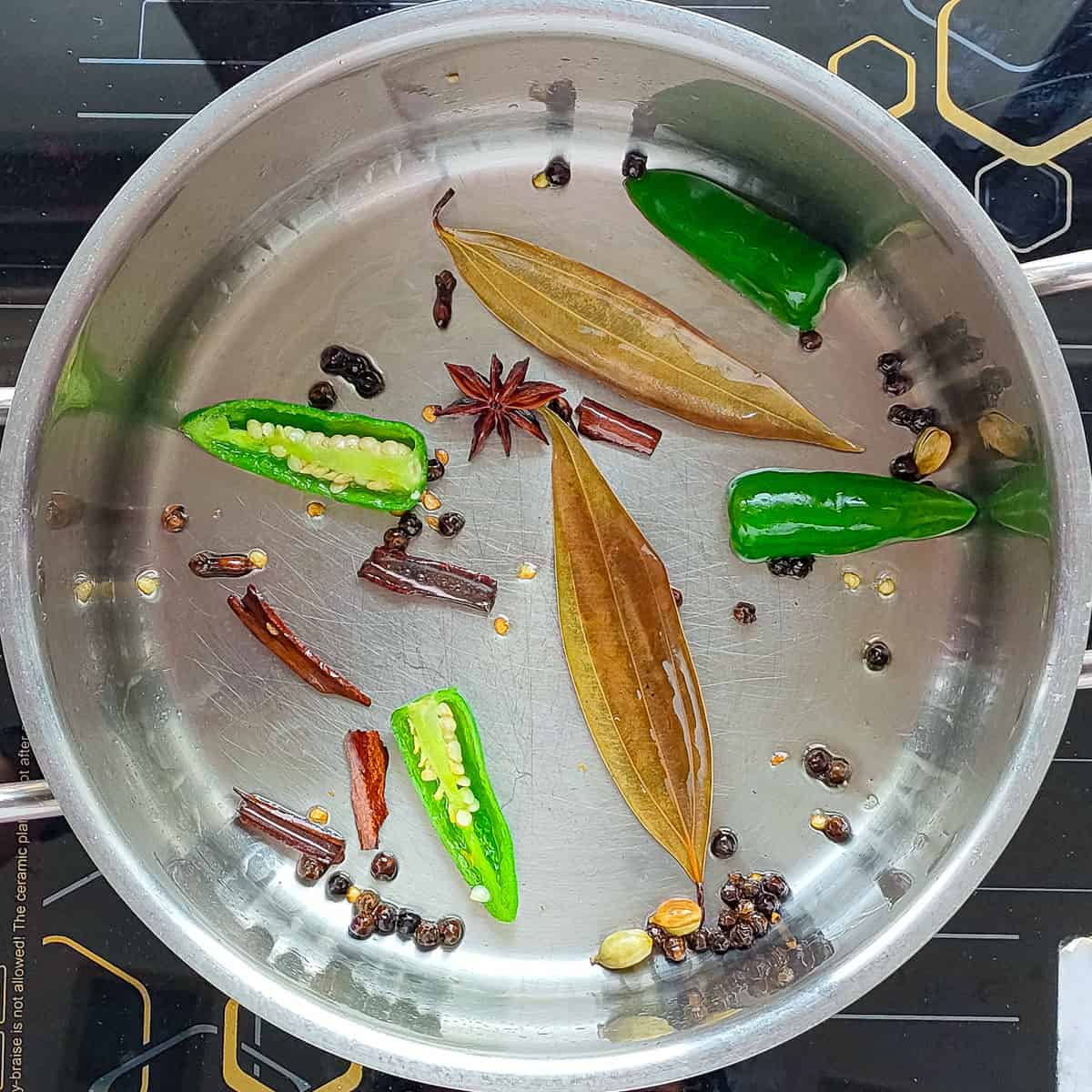 Spices being sauteed in a metal soup pot for chicken broth.