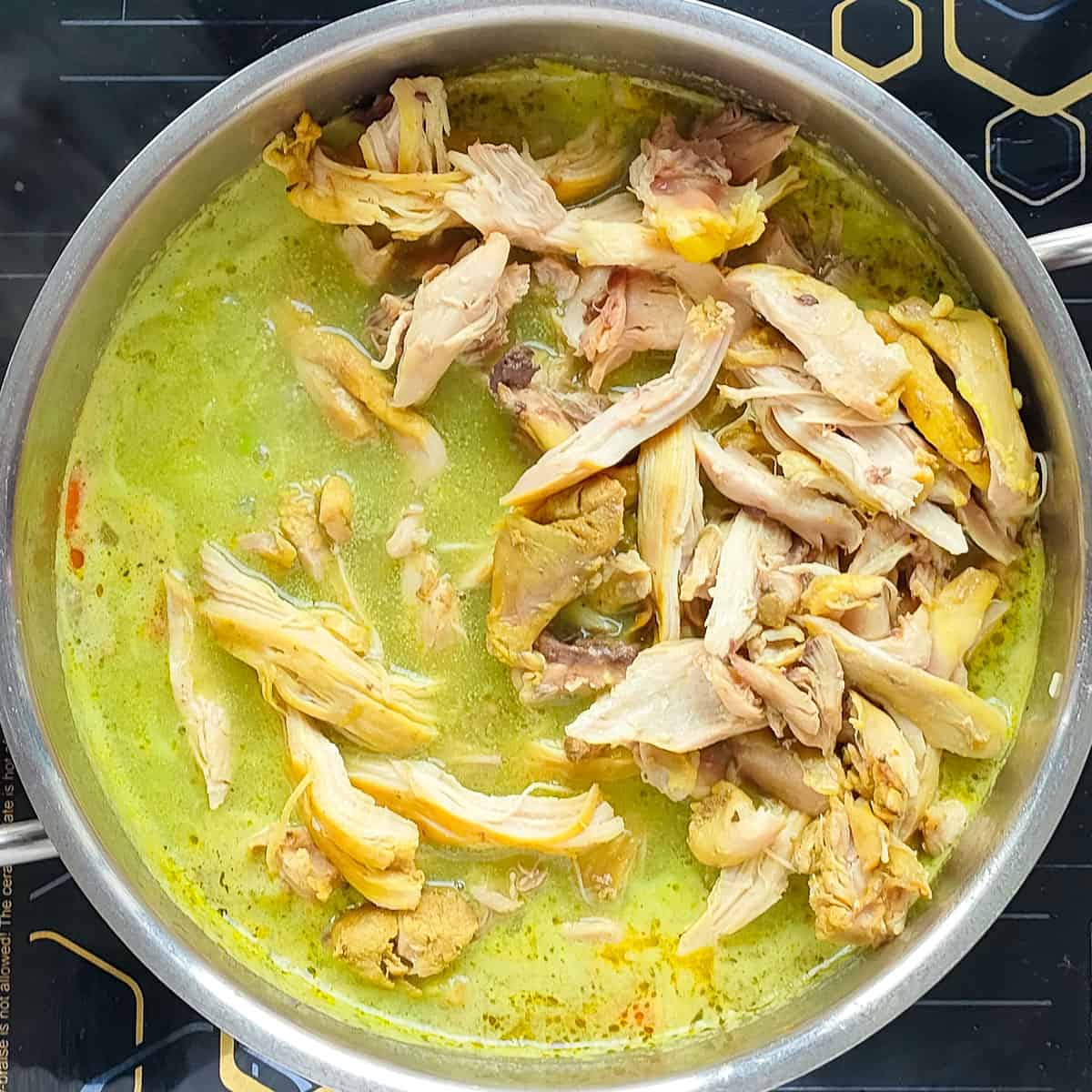 Coriander lemon soup with chicken in a white and blue bowl.