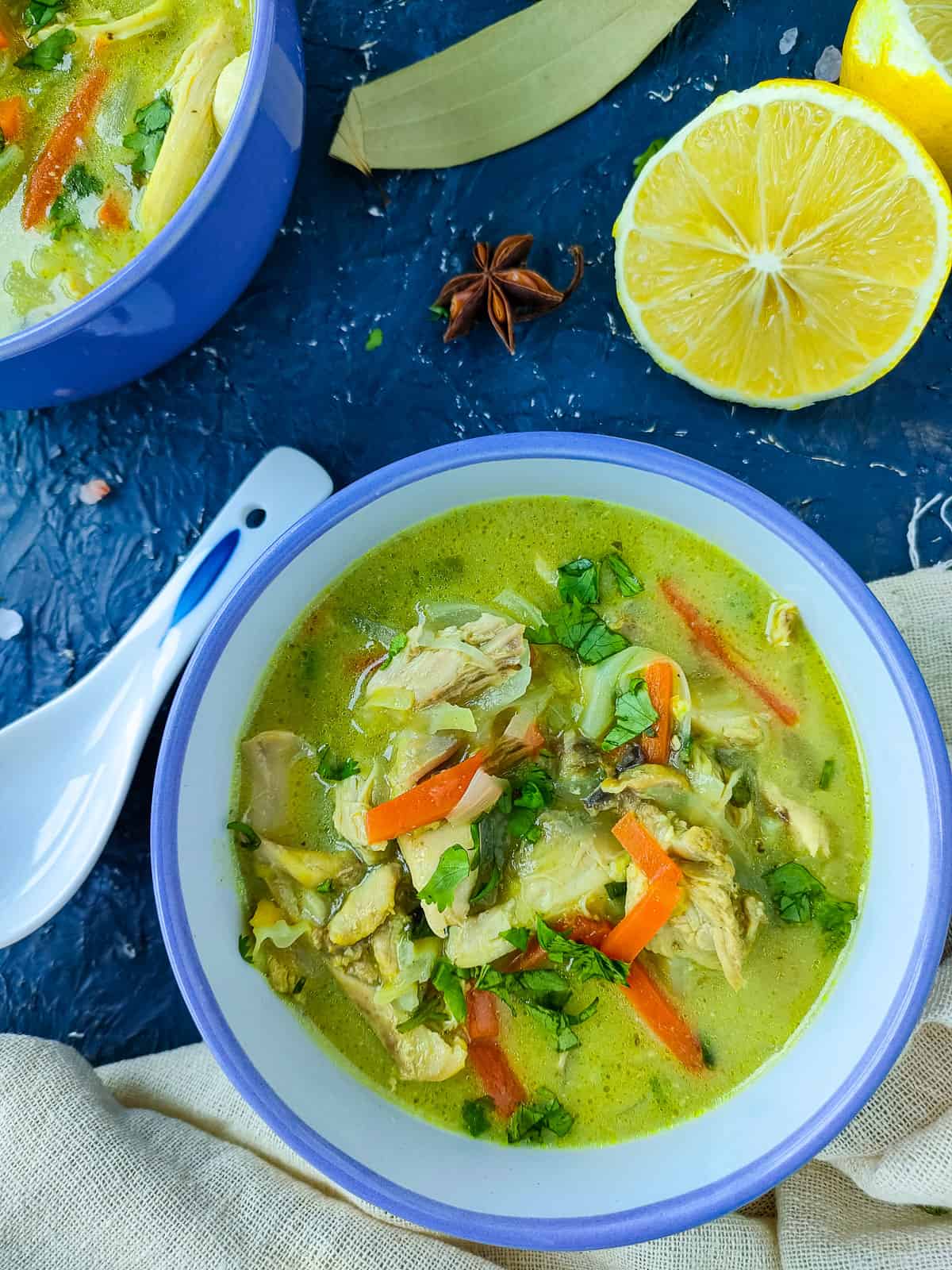 Chicken lemon coriander soup in a white and blue bowl.